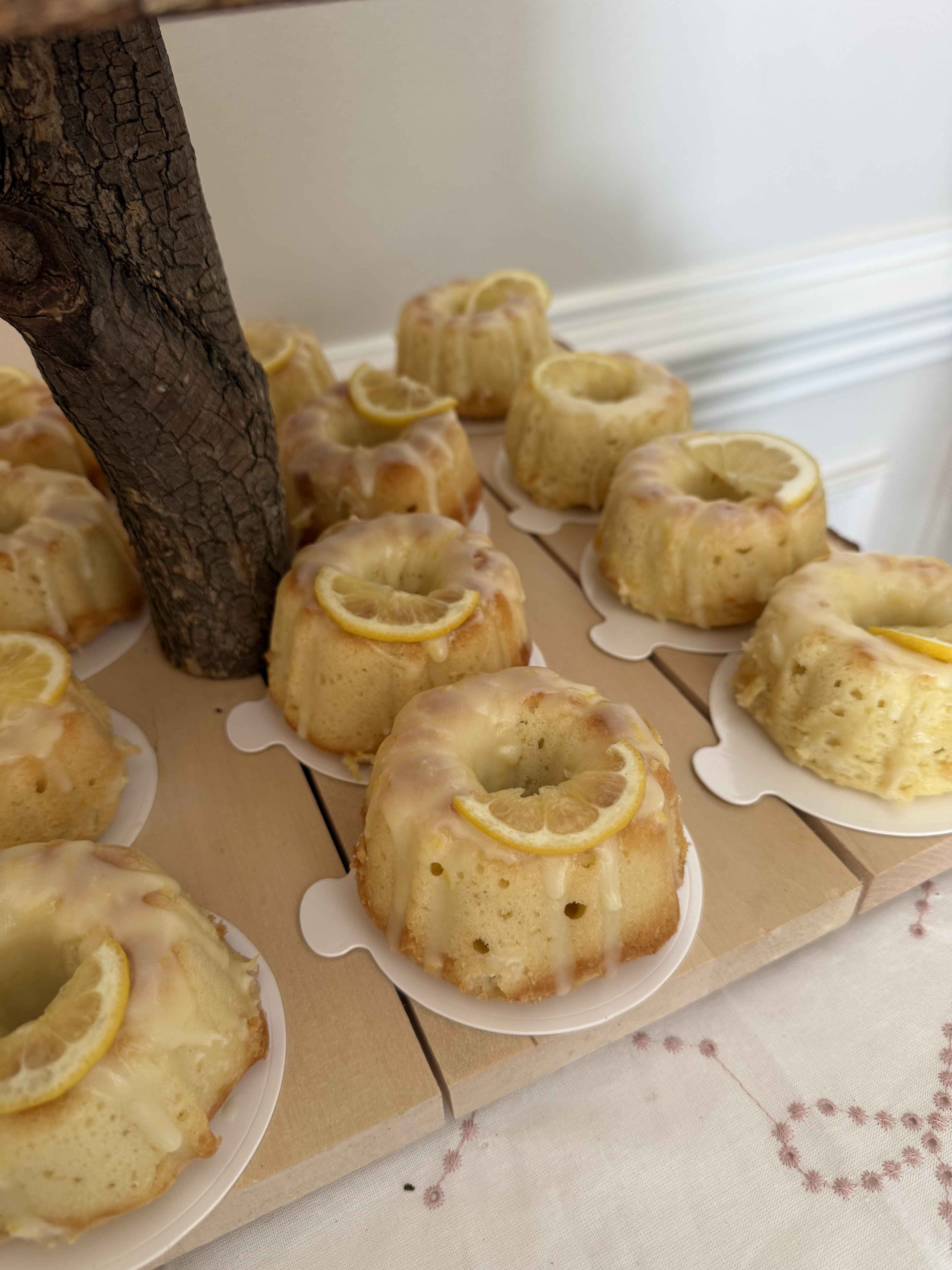 Glazed lemon bundt cakes on a tiered wooden stand at an event