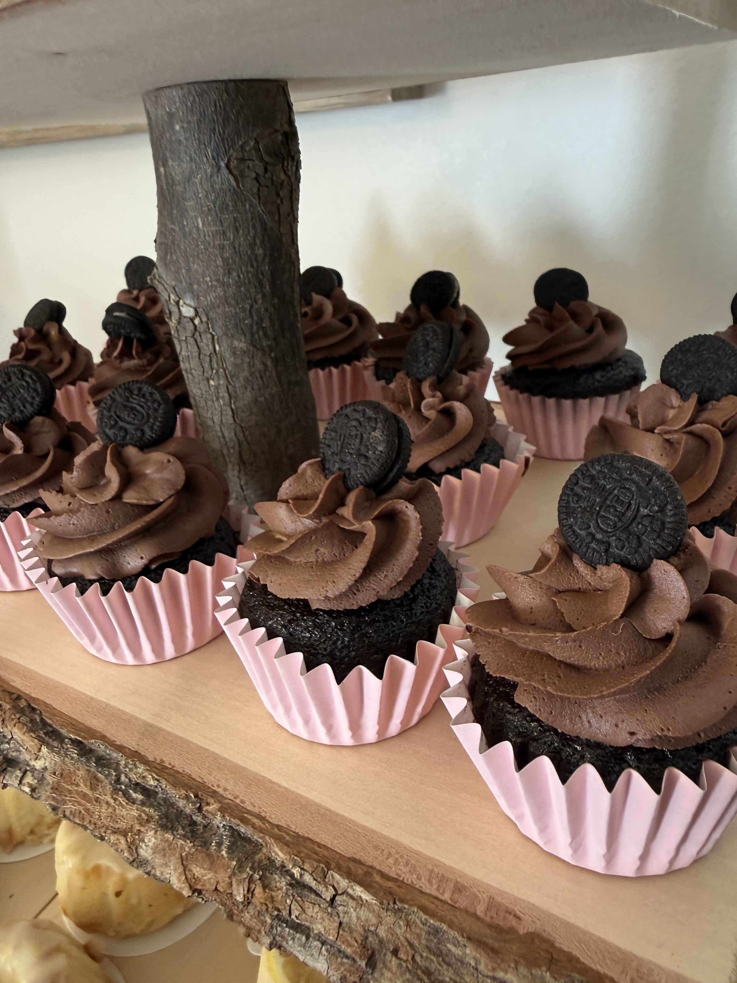 Chocolate Oreo cupcakes arranged on a rustic wooden dessert stand